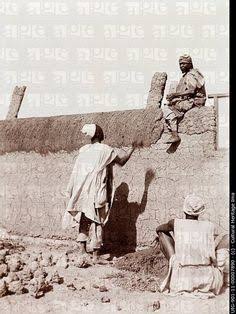 Hausa builders putting final touches to a mud wall.
