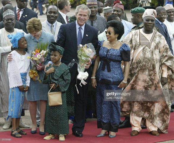 US President George W. Bush (C), US First Lady Laura Bush (2nd-L), Nigeria's President Olusegun Obasanjo (R), and Nigeria's First Lady Stella Obasanjo (2nd-R) are presented flowers by children at an arrival ceremony at the Presidential Villa in Abuja, Nigeria, 12 July 2003. via Getty Images)