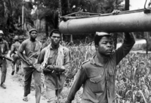 A Biafran Soldier transporting locally made ogbunigwe rocket